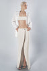 Woman wearing a beige linen cotton bra crop top with matching low-waist maxi skirt and white shirt