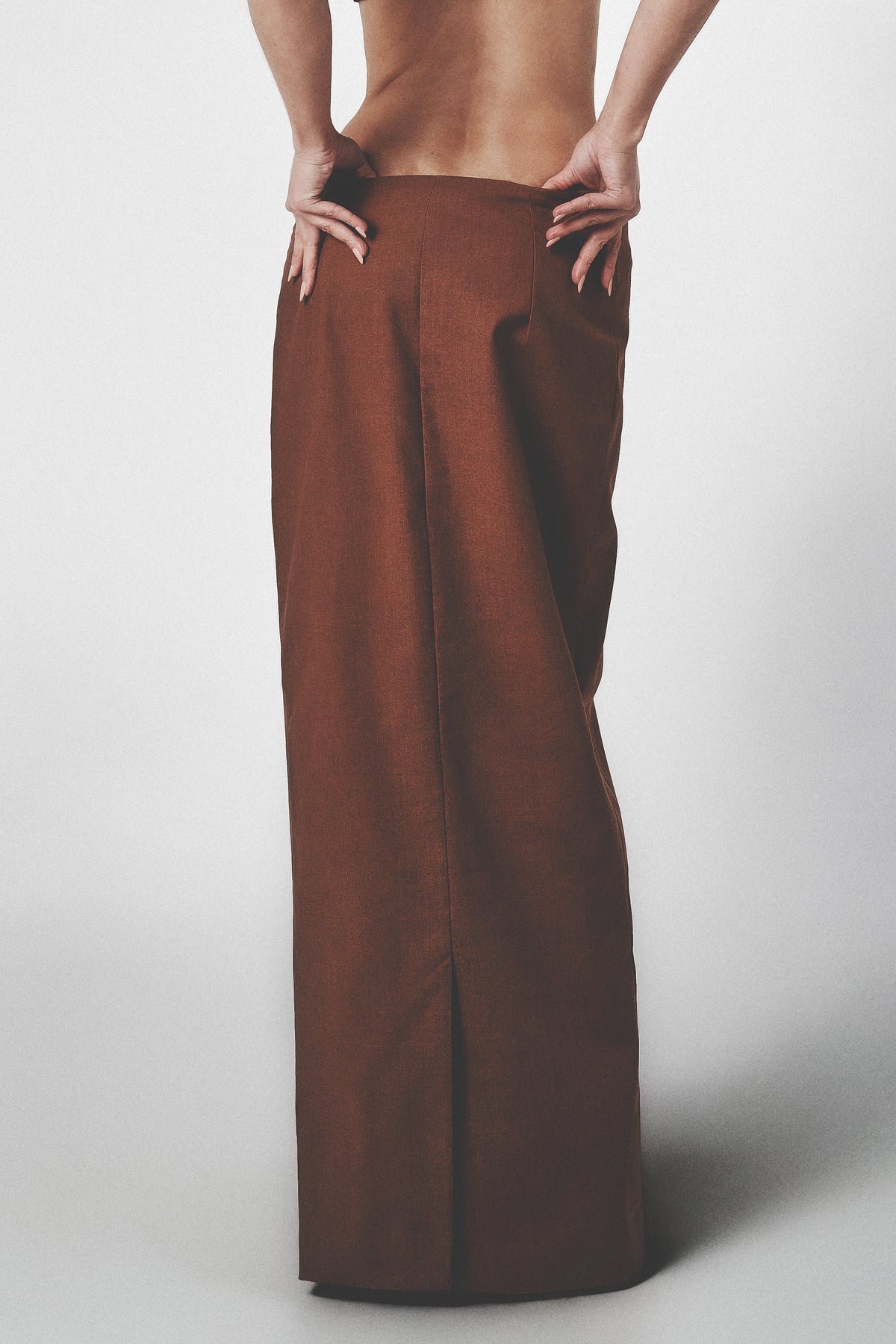 Side view of the brown low-rise maxi skirt showing its straight full-length cut