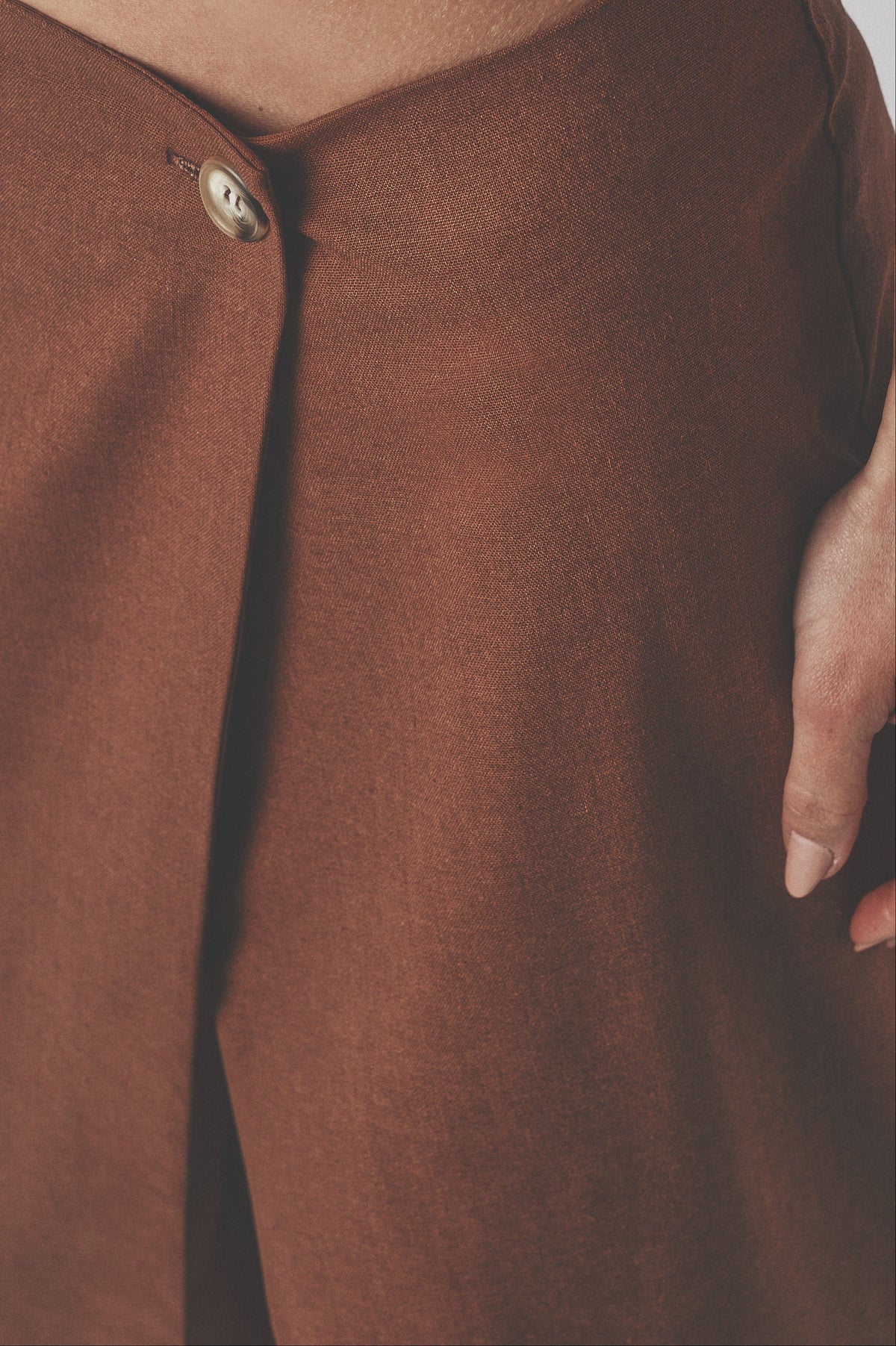 Close-up of the brown low-waist maxi skirt showing the front closure and linen cotton fabric