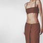 Woman wearing a brown structured bra crop top with slim straps and matching maxi skirt