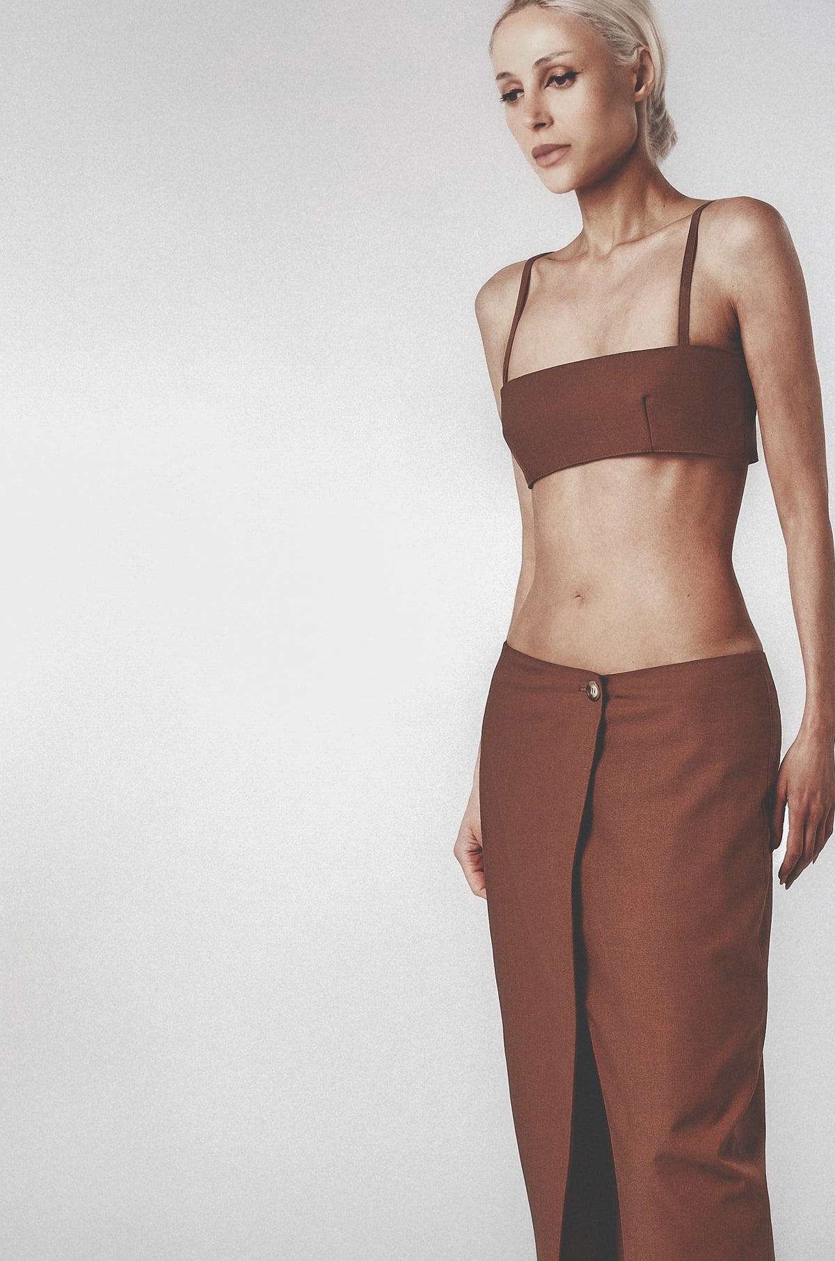 Woman wearing a brown structured bra crop top with slim straps and matching maxi skirt