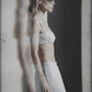 Woman wearing a light blue bra crop top and matching maxi skirt in an editorial image